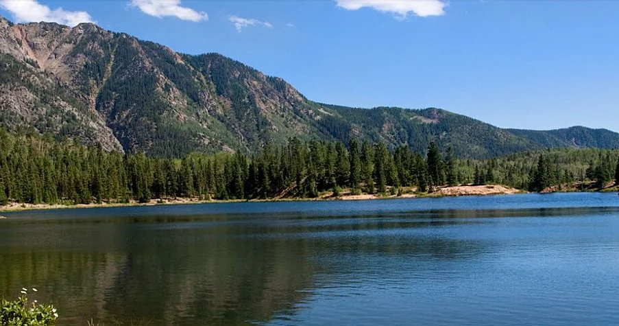 A calm mountain lake ringed by pines in the San Juan Mountains