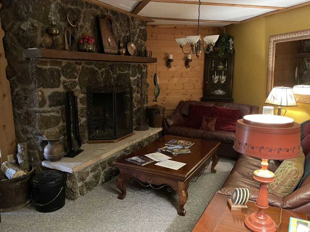 Leather couches before the stone fireplace at Country Sunshine Bed & Breakfast